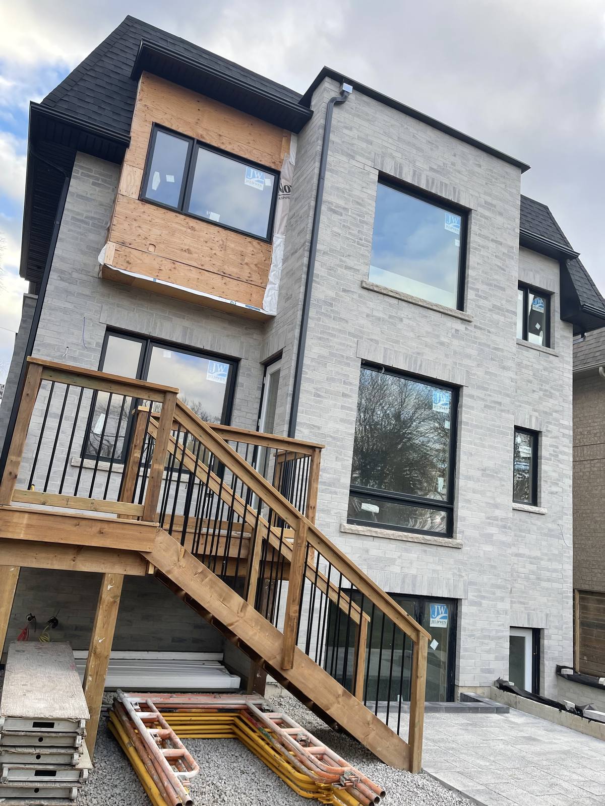 Rear facade of a Berm Inc. custom home with black-framed windows, second-storey deck and stairs
