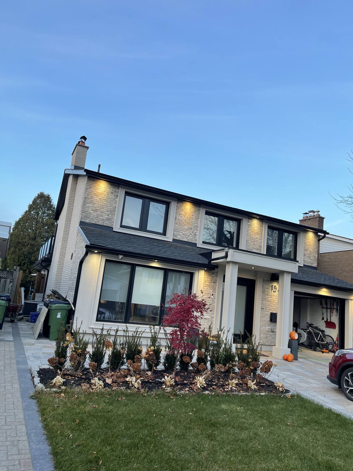 Completed two-storey custom home — brick veneer, covered entry portico and interlocking stone driveway — Berm Inc.